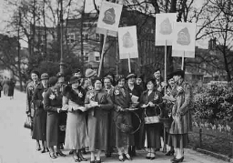 Vrouwen met protestborden met tekst: 'Propaganda week van het comité ter bevordering van de waardering van vrouwenarbeid in het gezin en maatschappij 28 maart - 4 april' 1935