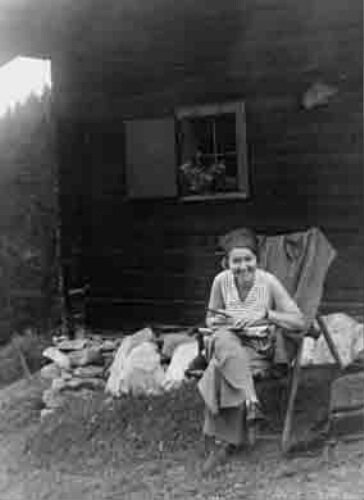 Portret van een vrouw bij een houten huisje. 1934
