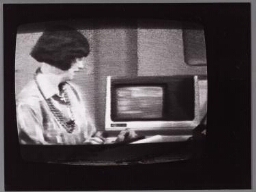 Foto van TV met vrouw die uitleg geeft over computers. 198?