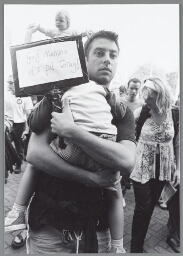 Man met kind op de arm en spandoek: 'Geef mama d'r pil terug!' tijdens de manifestatie 'Keer het Tij', tegen de bezuinigingsplannen van het kabinet Balkenende II. 2003