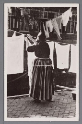 Vrouw in Volendamse klederdracht hangt de was op. 1900?