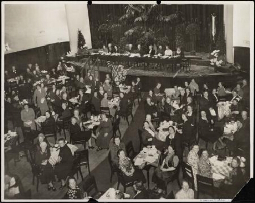 Overzichtsfoto van de zaal en het podium tijdens de Algemene Vergadering van de Nederlandse Vereniging van Huisvrouwen in Leeuwarden. 1940