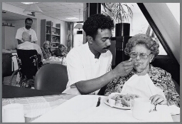 Verzorger in verpleeghuis Megropa geeft een oude dame te eten. 1991