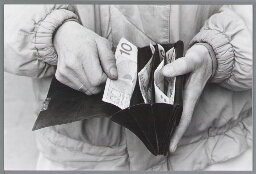 Persoon toont inhoud van portemonnaie, waaronder een biljet van 10 gulden. 198?
