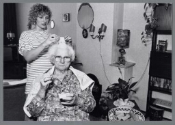 Thuiszorg : een hulp zet krulspelden in het haar van een oude dame. 1991