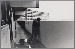 Een vrouw hangt tegen de leuning van een galerij aan. 1981