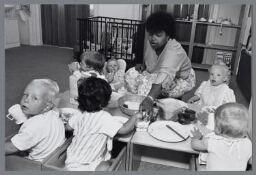Begeleidster van gemeentecrèche 'Okki' met kinderen aan het eten. 1989