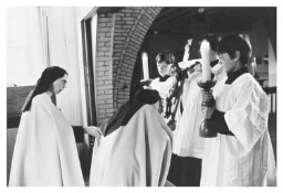 Carmelitessen kussen een kruis die een koorknaap vasthoudt. 1982