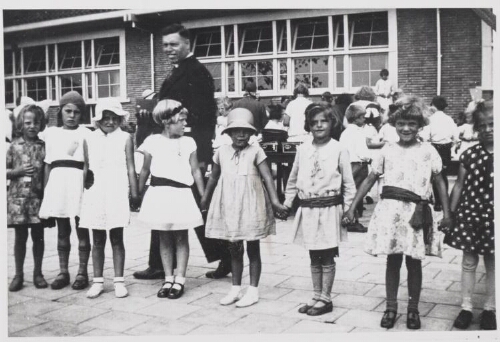 Groepsportret van meisjesleerlingen met hun onderwijzer aan de School met de Bijbel op het schoolplein. 1933?