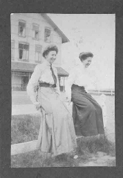 Jonge vrouwen zittend op een hek tijdens een zomerkamp 1911