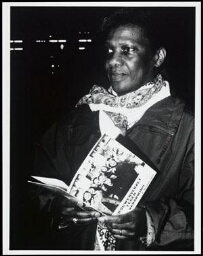 Portret van een zwarte vrouw die de brochure 'Vrouwenverzet tegen verarming' in haar hand heeft, uitgegeven ter gelegenheid van Internationale Vrouwendag op 8 maart 1989 1989