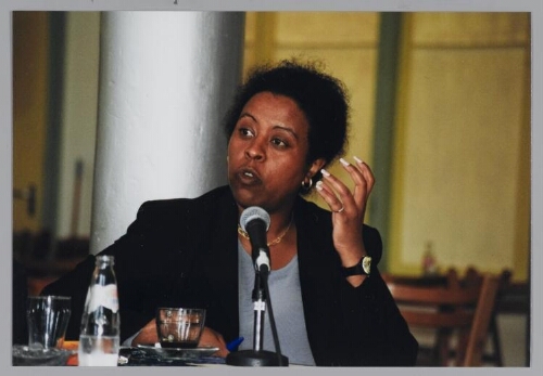 Domenica Ghidei Büdu, jurist en schrijfster van het boek 'Door het oog van de naald', over de praktijk van de asielprocedure, tijdens Café Zamicasa over beeldvorming en vreemdelingenbeleid. 1999