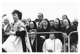 Zusters wachten achter hekken op een processie. 198?