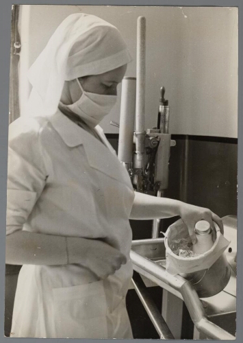 Verpleegkundige doet voor export bestemde moedermelk in een koelbox. 1937