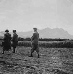 Twee heren en een dame lopen in een landschap 1938