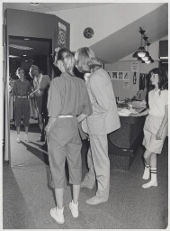 Verkoper helpt klanten in een kledingwinkel. 1982