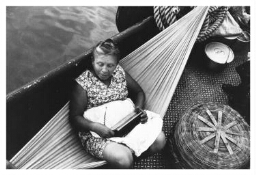 Tijdens een overtocht met een boot luistert een vrouw, zittend in een hangmat, naar de radio. 1984