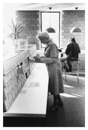 Een vrouw doorzoekt bibliotheekkaartjes. 198?