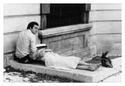 Een vrouw ligt met haar hoofd op de schoot van een man die aan het lezen is. 197?