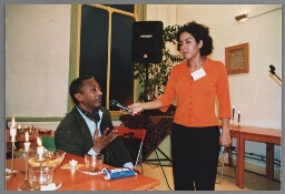 Naima Azough laat onbekende meneer aan het woord tijdens de nieuwjaarsborrel van Zami 2002 over vluchtelingenvrouwen in samenwerking met MCE (Projectbureau Multiculturalisatie en Emancipatie, voorheen Emancipatiebureau Amsterdam). 2002