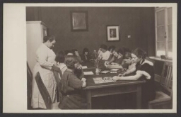 Meisjes doen een spelletje aan tafel in het tehuis der 'Vrouwenwelvaartspolitie' 193?