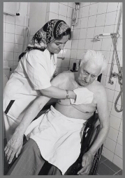 Allochtone vrouw werkzaam in verzorgingstehuis wast oude man. 1999