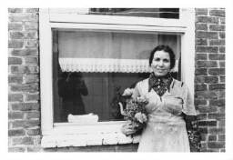 Marokkaanse vrouw voor het raam met een bloemetje in haar hand. 1980