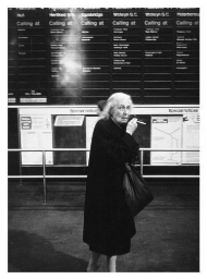 Vrouw voor een bord met haltes van een trein of metro in Engeland. 197?