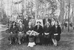 Johanna Westerdijk (zittend derde van rechts) en haar medewerkers in de tuin van villa Java met een bloemstuk aan haar voeten 1930