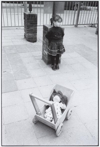 Foto van een meisje met lappenpop in karretje op een (speelplaats) gemaakt ter gelegenheid van een congres van de vakbond FNV over kinderopvang. 1989