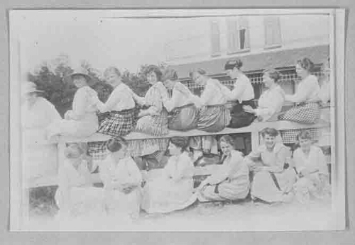 Groep jonge vrouwen zittend op een hek tijdens een Gildeconferentie? van de JVG 1920