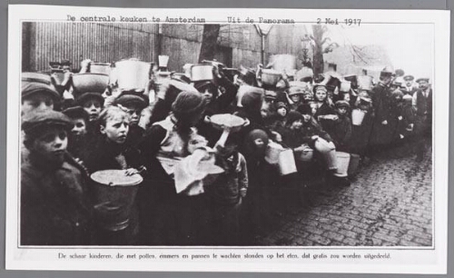 Voedselverstrekking: de centrale keuken te Amsterdam Bijschrift: 'De schaar kinderen, die met potten, emmers en pannen te wachten stonden op het eten, dat gratis zou worden uitgedeeld.' 1917
