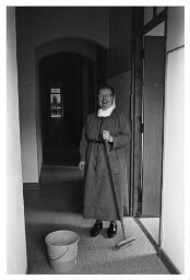 Clarissen Coletin in haar werktenue aan het schoonmaken. 1985