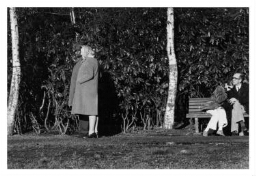 Een zwarte man en een blanke vrouw lopen langs een paar op een bank in het park. 198?