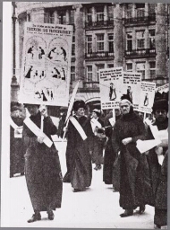 Leden van de afdeling propaganda van de Vereeniging voor Vrouwenkiesrecht met borden met: 'Sluit U allen aan bij den Optocht der Vereeniging voor Vrouwenkiesrecht - Zondag 18 juni IJSCLUB 12 uur' 1916