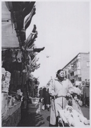 Bijschrift: 'Een migrantenvrouw loopt samen met haar kinderen over de markt' 199?