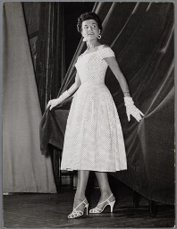 Vrouw toon spikkeltjes-jurk met bijpassende handschoenen. 195?
