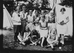 Groepsportret van elf vrouwen voor tent. 1930