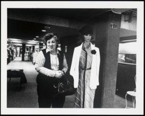 Vrouw naast een paspop in een modezaak 198?