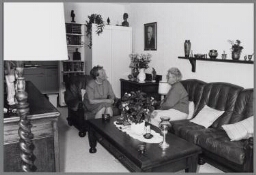 Twee vrouwen zitten in een woonkamer op de bank 1990