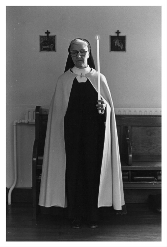 Een zuster van de orde van Carmel bid met een kaars in haar hand. 1983
