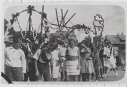 Leerlingen aan de School met de Bijbel lopen in optocht met versierde bogen, hoogstwaarschijnlijk ter gelegenheid van Koninginnedag. 1933?