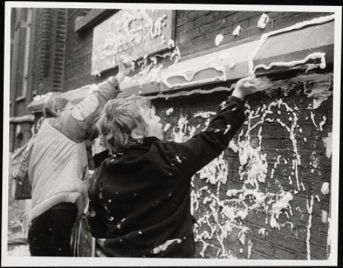 Twee vrouwen spuiten slagroom op de gevel van het Gemeentelijk Energie Bedrijf 1983