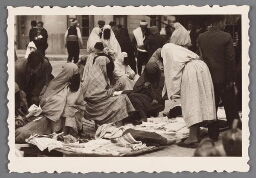 Vrouwen met abaya en sluier die het gehele gezicht bedekt verkopen doeken op de markt in Sarajevo. 193?