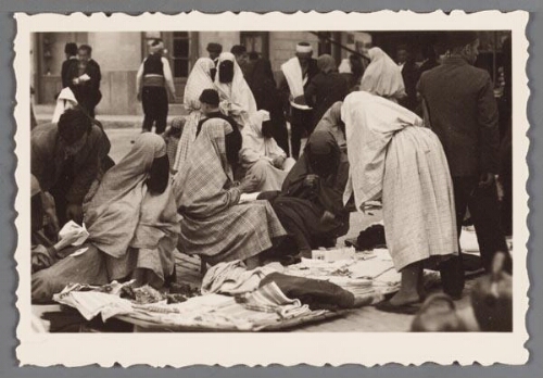 Vrouwen met abaya en sluier die het gehele gezicht bedekt verkopen doeken op de markt in Sarajevo. 193?