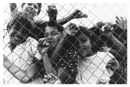Kinderen verdringen zich achter een hek. 1984