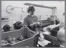 Vrouw schilt uien in een groentewinkel. 1985