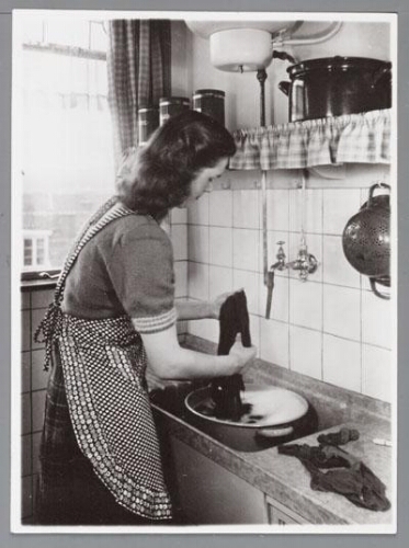 Vrouw doet de was op de hand in een teiltje in de keuken 195?