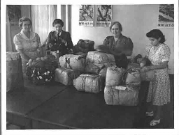 Bijschrift: 'Vier van ons in actie wol pakkende voor de verschillende takken van de S.A.W.A.S in de Transvaal voor Kleren voor Holland 1944