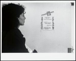 Vrouw kijkt naar een affiche van de Vrouwensteungroep op de muur 198?/199?